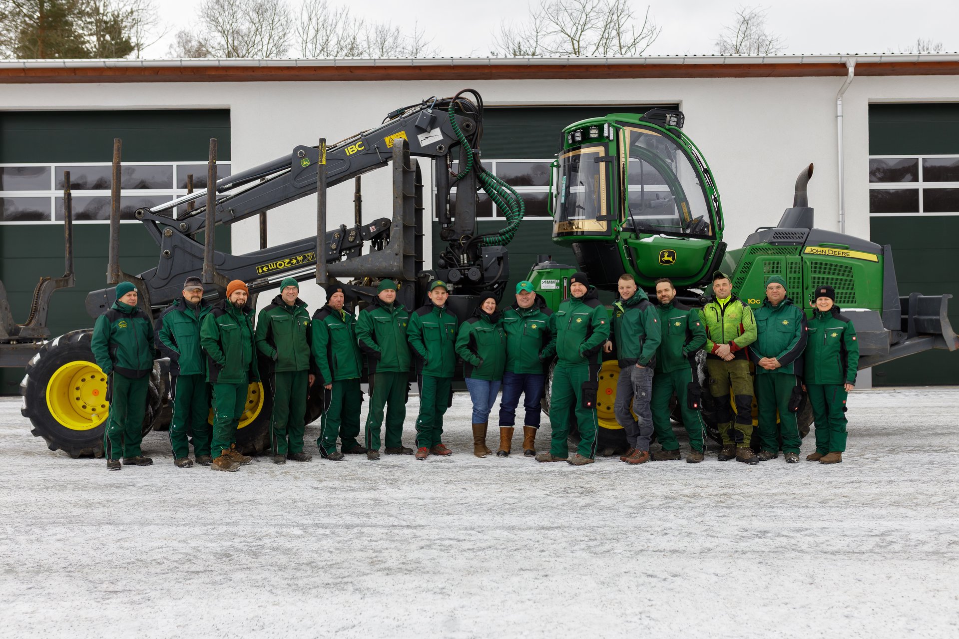 Forstbetrieb Thomas Behrisch – Das Team aufgereiht vor einem John Deere Forwarder auf dem Betriebshof