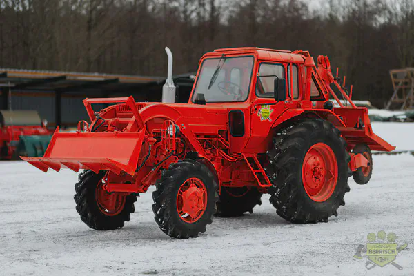 Restaurierter roter Forsttraktor mit Frontlader auf dem Betriebsgelände