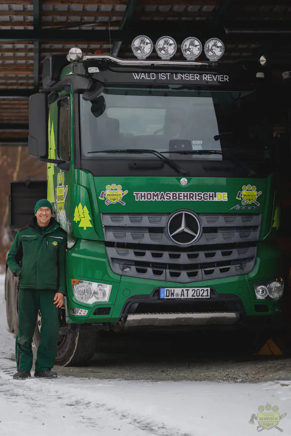 Mitarbeiter neben dem grünen Mercedes-Benz Firmen-LKW mit Aufschrift Wald ist unser Revier